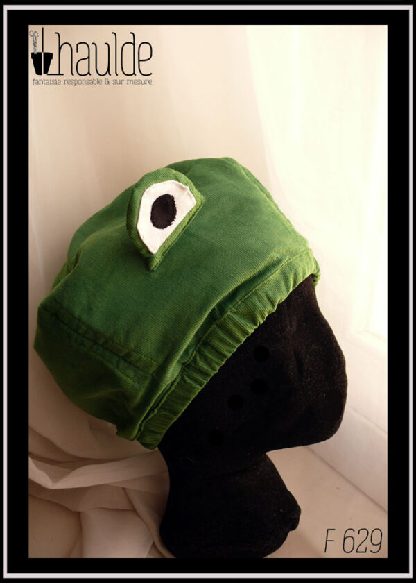 Bonnet en velours milleraies vert clair avec deux yeux sur le dessus pour figurer une tête de grenouille Vu de profil sur une tête de mannequin