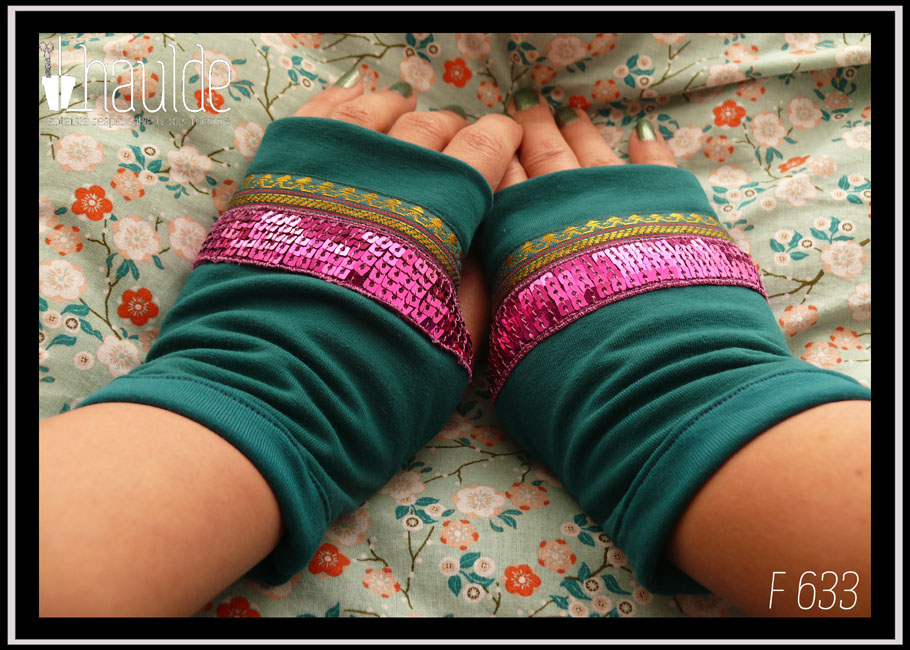 Mitaines en jersey bleu pétrole garnies au niveau de l'ouverture du pouce d'un galon brodé de doré et de pourpre (motifs abstraits) et d'un galon de 5 rangs de sequins carrés fuchsia Vue de dessus de la paire portée