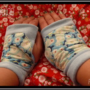 Mitaines en velours bleu pastel avec au milieu une large bande de tissu imprimé fleurs de cerisiers bleues stylisées Vue de dessus, portées