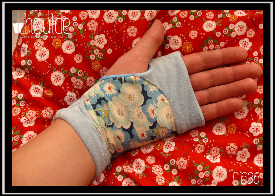 Mitaines en velours bleu pastel avec au milieu une large bande de tissu imprimé fleurs de cerisiers bleues stylisées Vue côté paume, portée