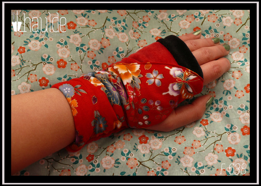 Mitaines longues en velours rouge avec en courbe côté pouce une bande de tissu rouge imprimé fleurs et papillons d'esthétique japonaise Une bande de velours noir marque les phalanges Vue portée, de dessus