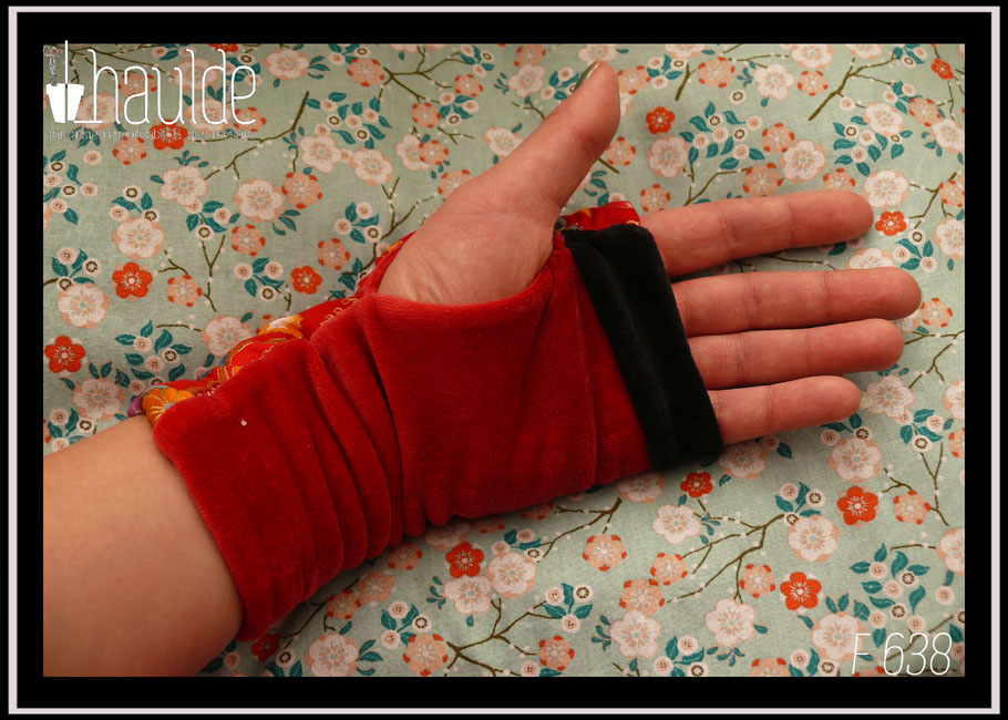 Mitaines longues en velours rouge avec en courbe côté pouce une bande de tissu rouge imprimé fleurs et papillons d'esthétique japonaise Une bande de velours noir marque les phalanges Vue portée, côté paume, velours rouge et bande noire, pas d'imprimé de ce côté