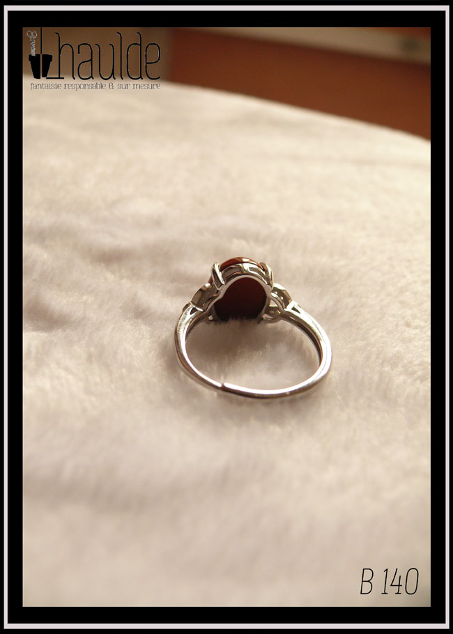 Bague avec un petit cabochon ovale en jaspe rouge monté sur un support en argent garni de chaque côté de trois petites mandorles contenant des éclats d'oxyde de zirconium Vue de dos, l'anneau est réglable