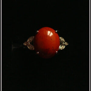 Bague avec un petit cabochon ovale en jaspe rouge monté sur un support en argent garni de chaque côté de trois petites mandorles contenant des éclats d'oxyde de zirconium Vue sur fond noir