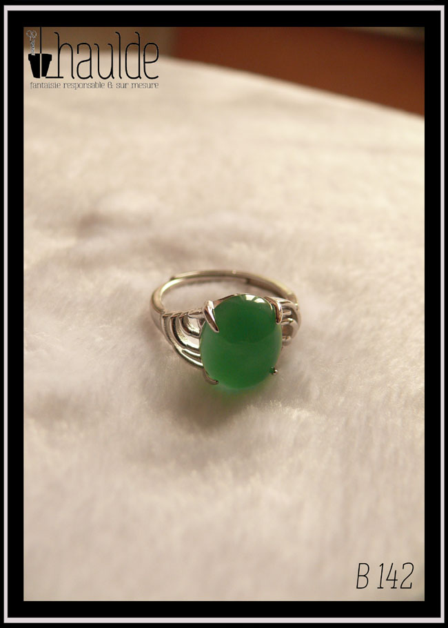Bague avec un petit cabochon ovale en aventurine vert foncé montée sur un support en argent dont les côtés sont ajourés. Vue sur fond blanc, de face, la pierre est translucide