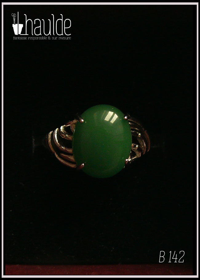 Bague avec un petit cabochon ovale en aventurine vert foncé montée sur un support en argent dont les côtés sont ajourés. Vue sur fond noir