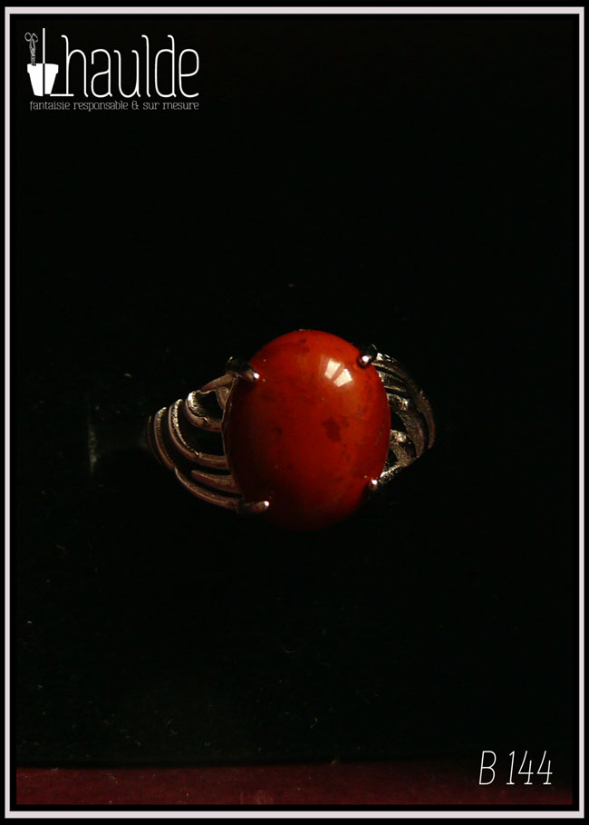 Bague avec un petit cabochon ovale en jaspe rouge montée sur un support en argent dont les côtés sont ajourés vue sur fond noir