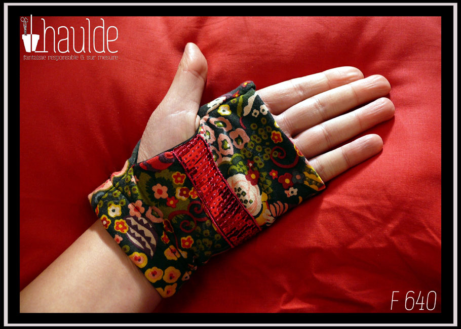 Paire de mitaines en jersey noir imprimé fleuri stylisé, dominante jaune et rouge, garnie en leur milieu d'un galon de sequins carrés rose fraise Vue côté paume