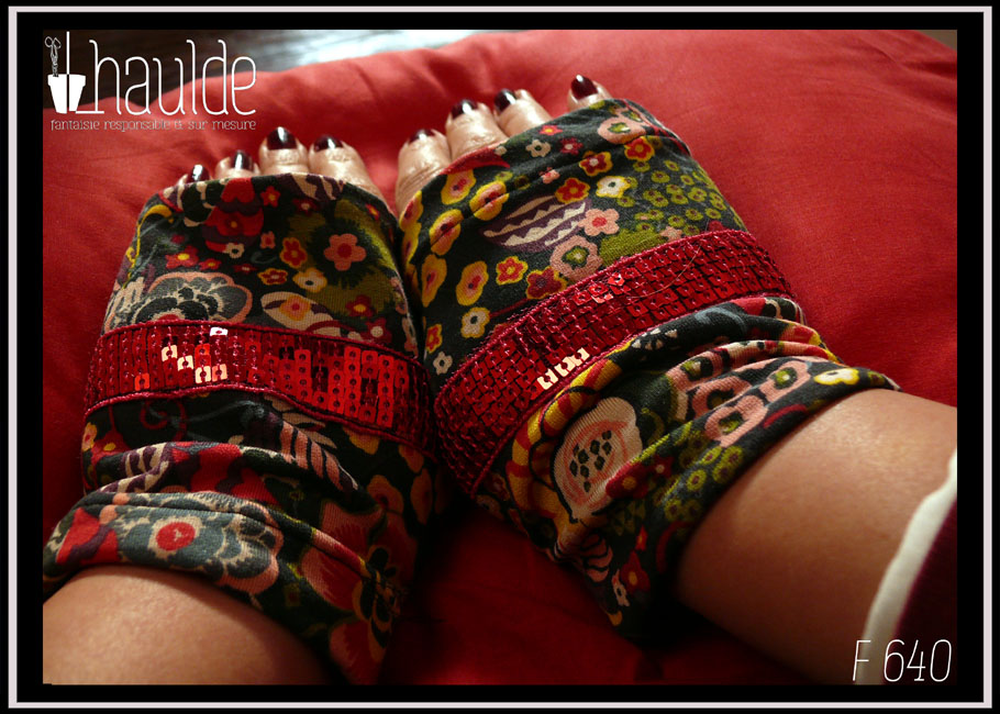 Paire de mitaines en jersey noir imprimé fleuri stylisé, dominante jaune et rouge, garnie en leur milieu d'un galon de sequins carrés rose fraise Vue de la paire portée