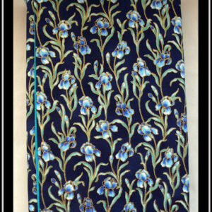 Protège livre en tissu bleu marine imprimé iris bleus; Les iris sont sur tige avec leurs feuilles et détouré d'une très fine ligne dorée Vu fermé
