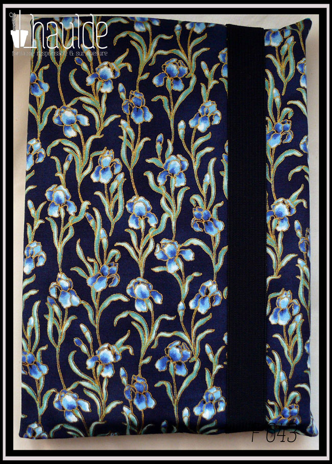 Protège livre en tissu bleu marine imprimé iris bleus; Les iris sont sur tige avec leurs feuilles et détouré d'une très fine ligne dorée Le protège livre est fermé par un gros élastique bleu nuit