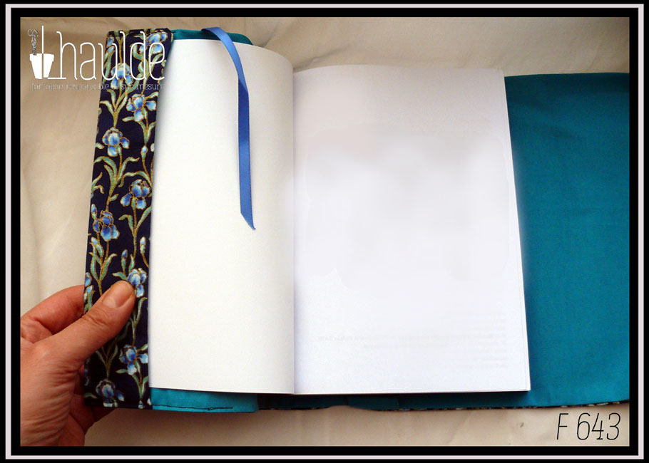Vue du protège livre ouvert, le signet en satinette bleue est visible, à gauche le rabat du protège livre en tissu bleu marine imprimé iris bleus, à droite l'intérieur du protège livre, en tissu bleu cyan uni