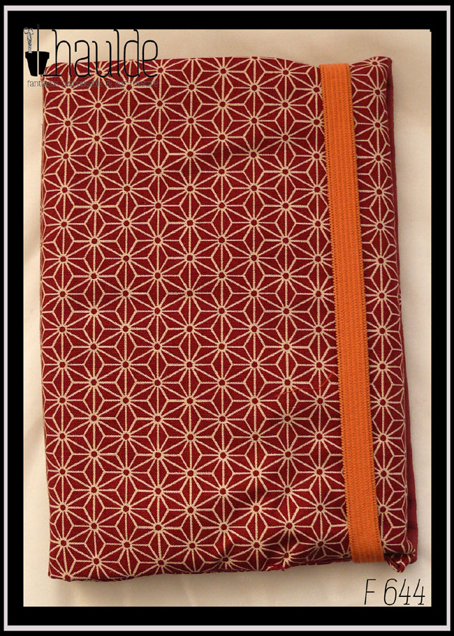 Protège carnet en tissu rouge brique foncé imprimé de motifs géométriques japonais en étoile écrus Vu fermé par un élastique orange