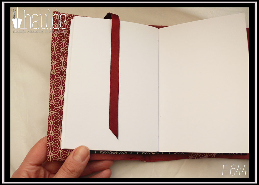Protège carnet en tissu rouge brique foncé imprimé de motifs géométriques japonais en étoile écrus Vu ouvert sur un carnet, le signet est rouge foncé