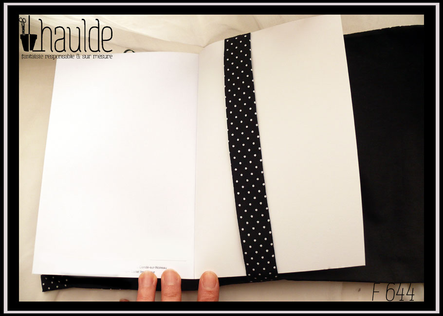 Protège livre en tissu noir à petits pois blancs Vu ouvert sur un livre, côté bande de maintien