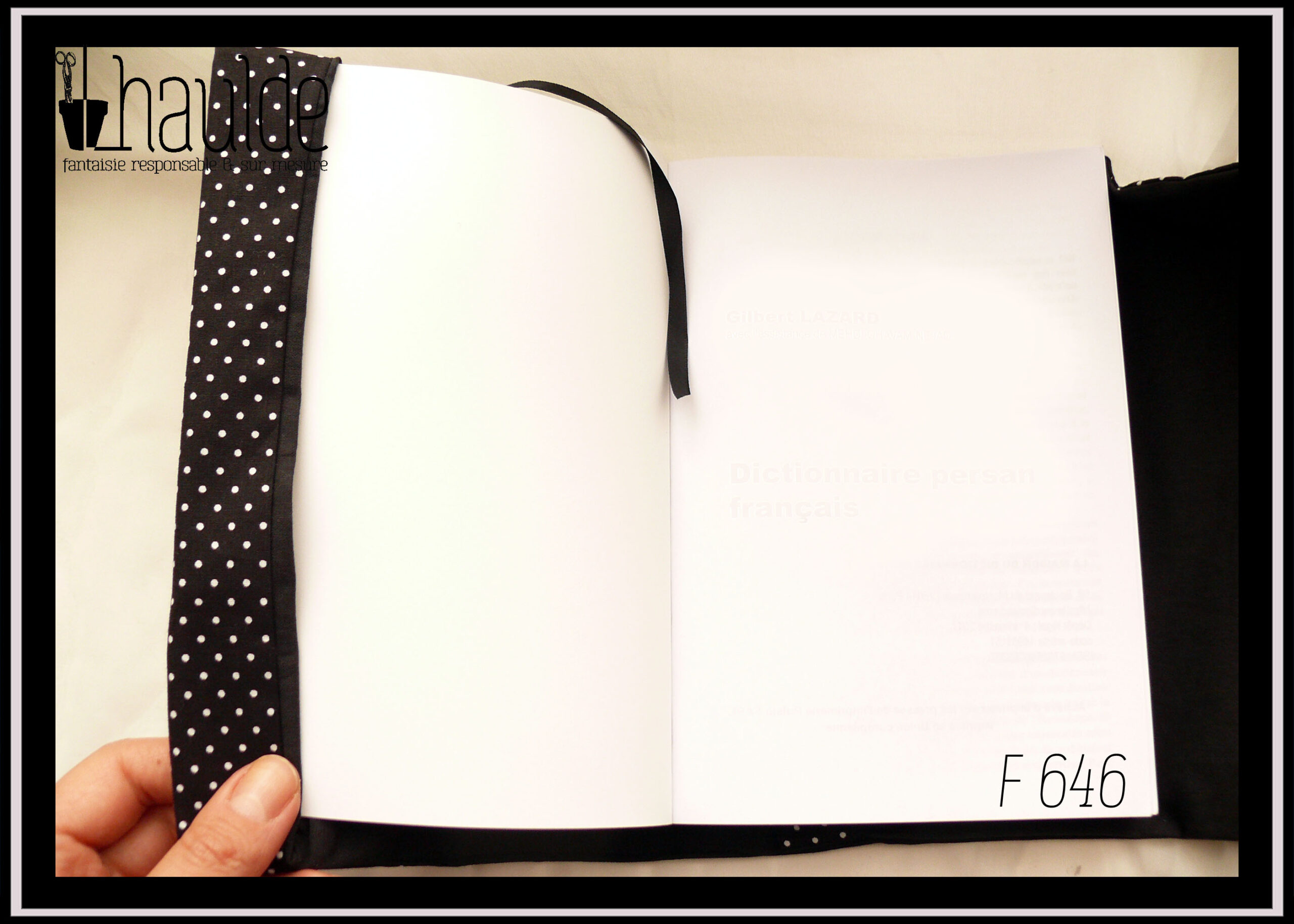 Protège livre en tissu noir à petits pois blancs Vu ouvert sur un livre, le signet et l'intérieur du protège livre sont noirs