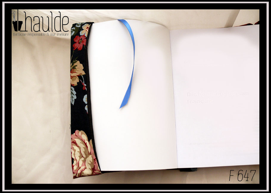 Protège livre en tissu noir imprimé hortensia rouges foncés et blancs Vu ouvert sur un livre, le signet est en satinette bleue