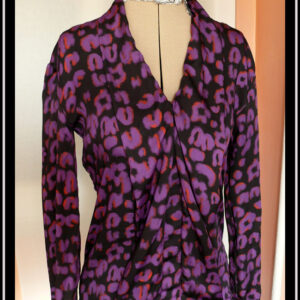 Chemisier à manches longues, col châle qui descend jusqu'en bas vu de face en tissu fluide noir imprimé motif panthère stylisé violet légèrement souligné de orange