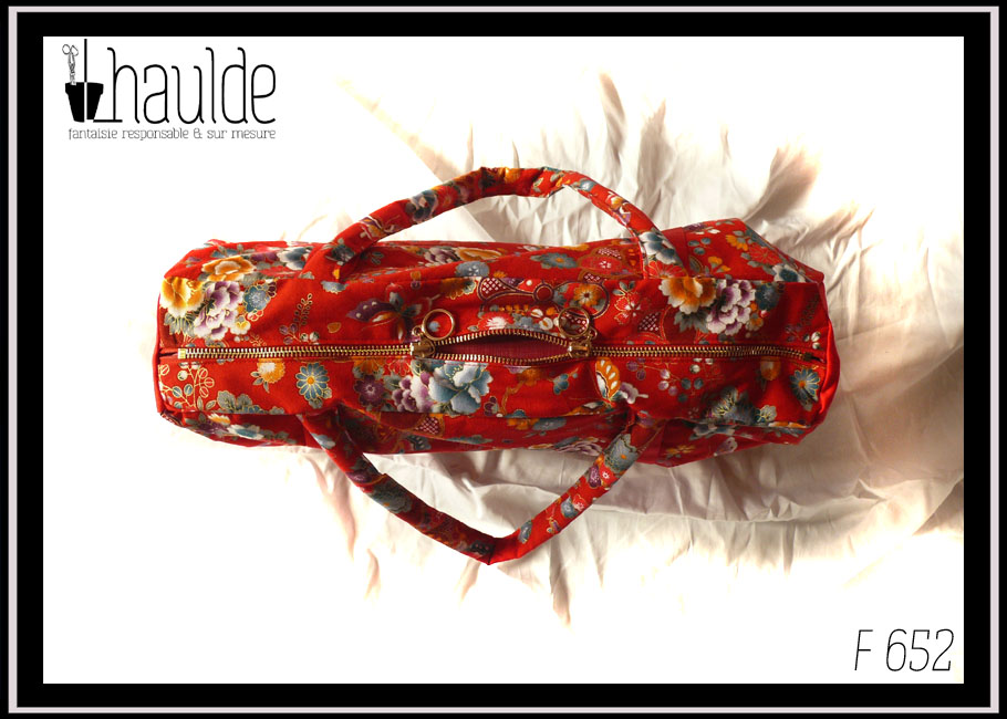 Grand sac en toile à anse. Tissu rouge imprimé pivoines et autres fleurs multicolores soulignées de dorées, d'inspiration Est asiatique (Chine ou Japon), petits côtés, dessous et bandes de renfort en sergé rouge vu de dessus, le zip à double curseur en anneaux est quasi fermé