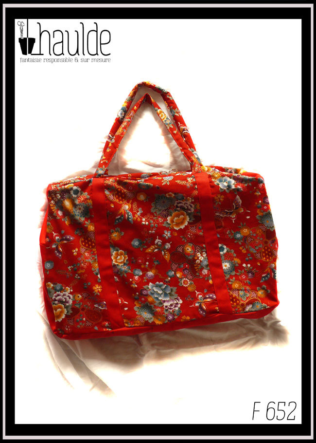 Grand sac en toile à anse. Tissu rouge imprimé pivoines et autres fleurs multicolores soulignées de dorées, d'inspiration Est asiatique (Chine ou Japon), petits côtés, dessous et bandes de renfort en sergé rouge Vu de dessus, couché sur un fond blanc