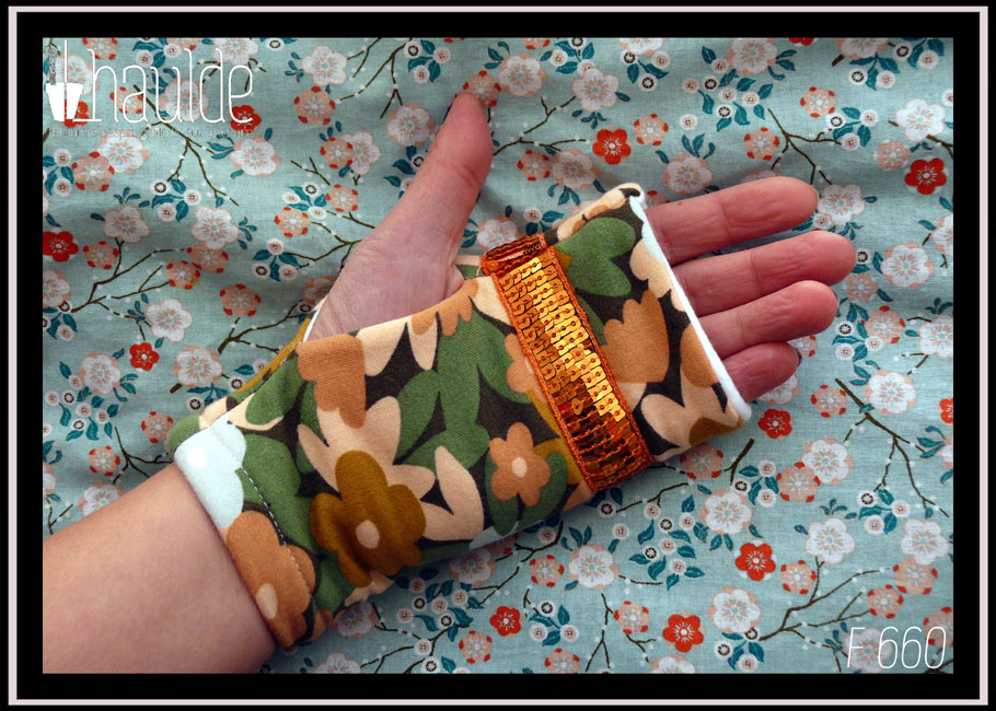 Mitaines en jersey gratté imprimé, fleurs ocre, corail, écru et bleu pâle sur fond noir avec feuilles vertes stylisées Un galon de sequins carrés oranges sur 5 rangs décore le dessus des phalanges Vue côté paume