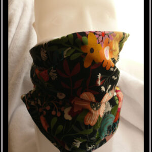 Tour de cou en jersey noir imprimé motifs fleuris multicolores. Vu sur une tête de mannequin, il tient facilement à hauteur de son nez