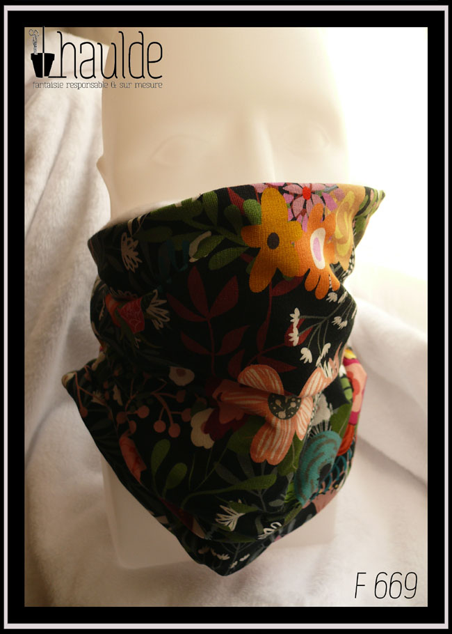 Tour de cou en jersey noir imprimé motifs fleuris multicolores. Vu sur une tête de mannequin, il tient facilement à hauteur de son nez