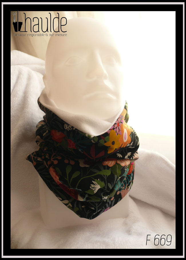 Tour de cou en jersey noir imprimé motifs fleuris multicolores. Vu de face sur une tête de mannequin, la doublure en polaire de coton blanc est visible