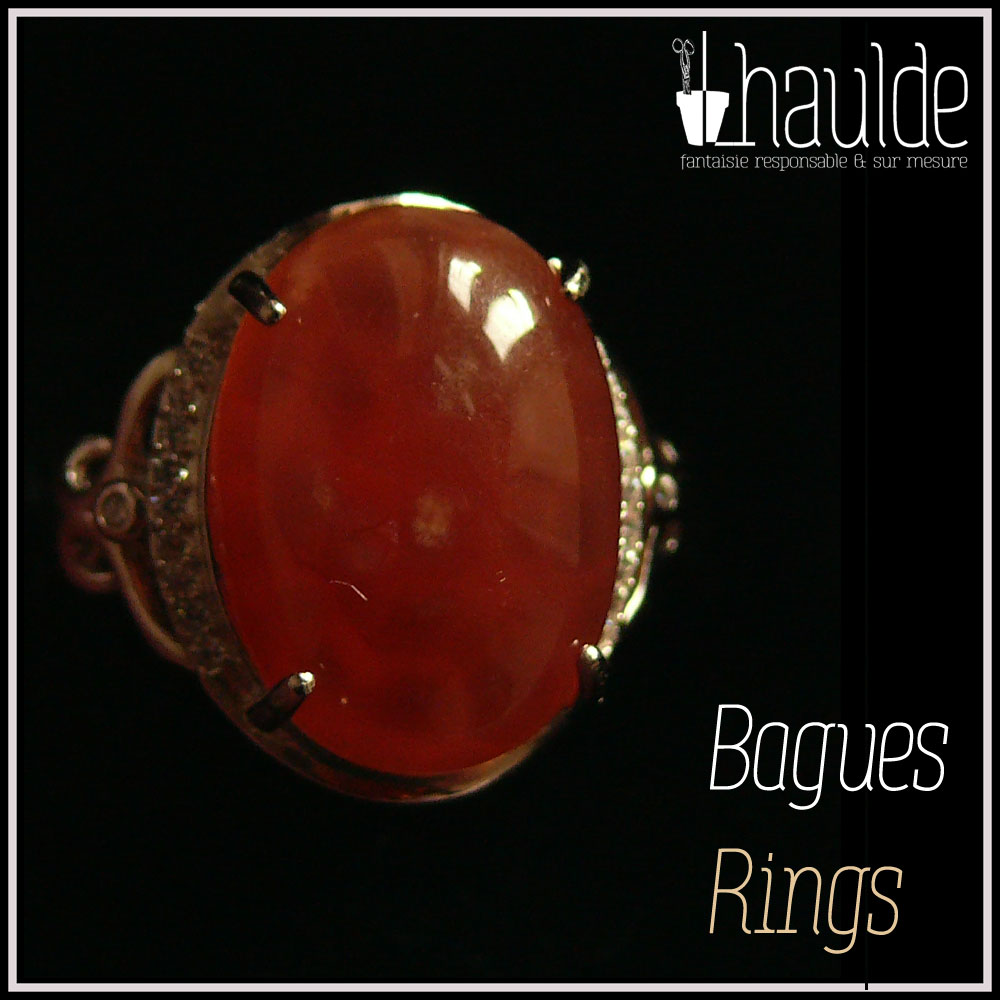 visuel de la catégorie bagues, une pierre naturelle rose-rouge translucide (de la rhodochrosite) montée sur un support en argent bordé de petits éclats d'oxyde de zirconium. Des arabesques font filer le dessus de la bague vers l'anneau réglable