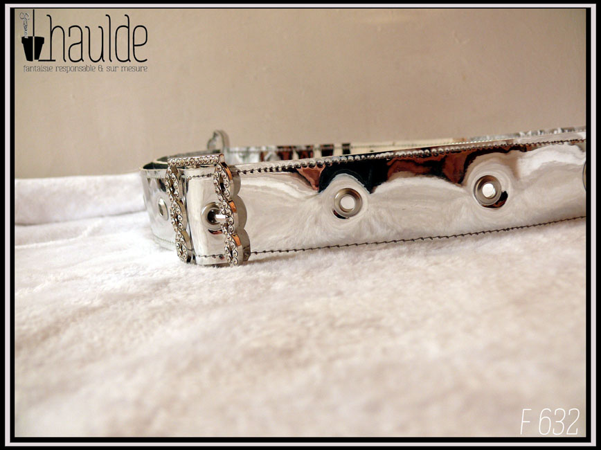 Une ceinture en simili cuir argenté rutilant avec une boucle rectangulaire décorée de strass Vue posée sur du doudou blanc