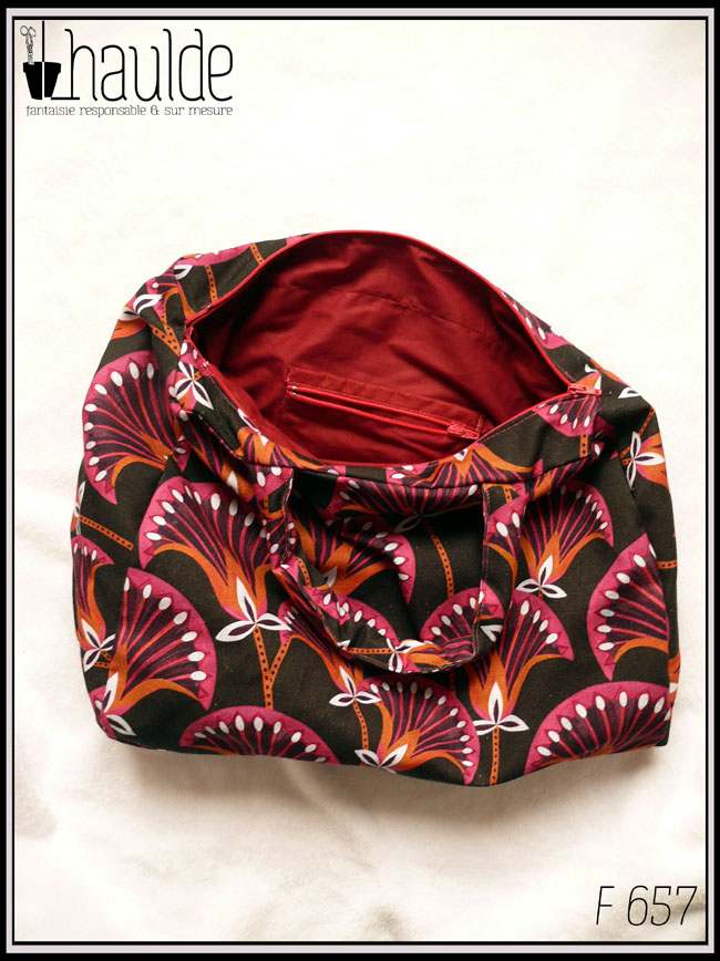 Sac en toile à anses. Toile noire motifs papyrus fuchsia et orange rehaussé de blanc Vu zip ouvert, l'intérieur est rouge bordeaux et il y a une poche intérieure, également zippée