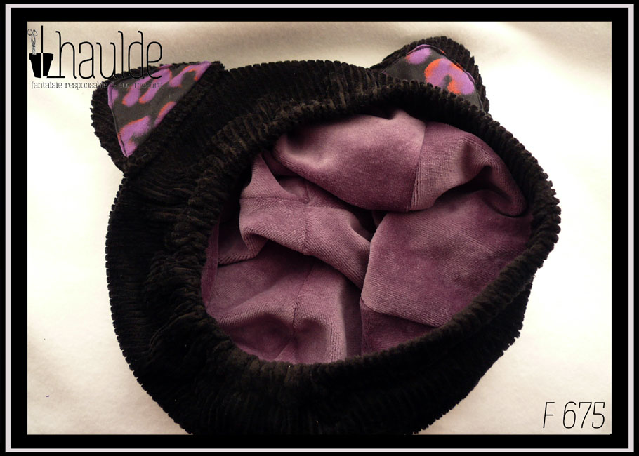 Vue de l'intérieur du bonnet, du velours ras mauve Bonnet en velours côtelé noir avec deux oreilles de chats dont l'intérieur est garni de tissu noir imprimé motifs panthère stylisé violet légèrement soulignés de orange