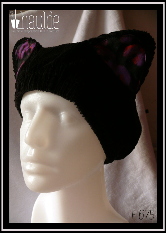 Bonnet en velours côtelé noir avec deux oreilles de chats dont l'intérieur est garni de tissu noir imprimé motifs panthère stylisé violet légèrement soulignés de orange Vu sur une tête de mannequin de trois quarts face