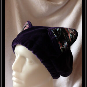 Bonnet en velours violet avec deux oreilles de chats dont l'intérieur est garni de tissu noir imprimé motifs oiseaux et fleurs dans les tons roses et bleus, avec une esthétique d'estampe japonaise Vu sur une tête de mannequin de trois quarts face