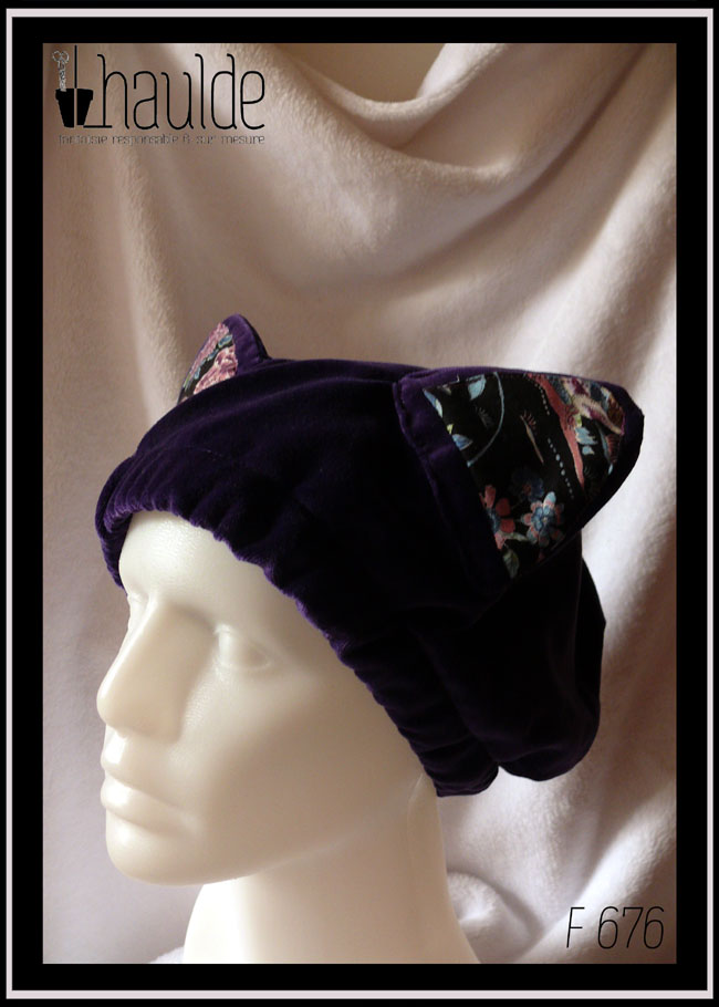 Bonnet en velours violet avec deux oreilles de chats dont l'intérieur est garni de tissu noir imprimé motifs oiseaux et fleurs dans les tons roses et bleus, avec une esthétique d'estampe japonaise Vu sur une tête de mannequin de trois quarts face