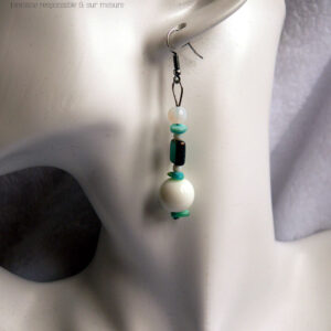 boucles d'oreilles montées sur crochet, perles en verre alignées à la verticale, perle ronde blanche opalescente, chips de couleur turquoise, perle carrée turquoise à tranche dorée, petite perle blanche, chips couleur turquoise, grosse perle blanche, chips couleur turquoise Vue portée par une tête de mannequin