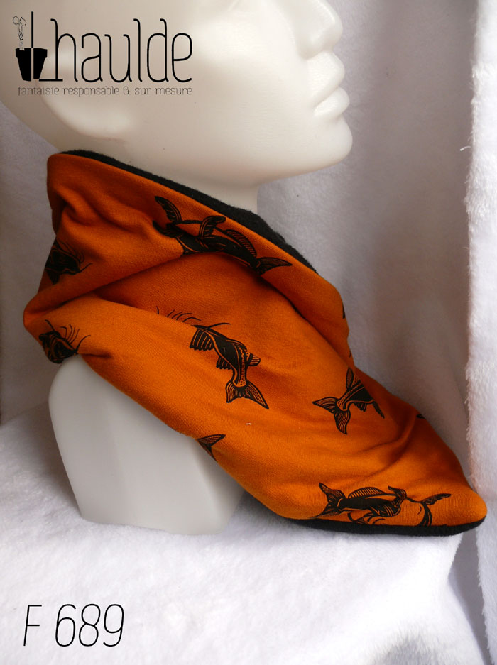 Cache col croisé, le côté droit sur le côté gauche, en jersey ocre foncé imprimé carpes noires (qui sont malheureusement mal orientées, tête en bas) Doublé de polaire de coton noir Vu de profil sur une tête de mannequin