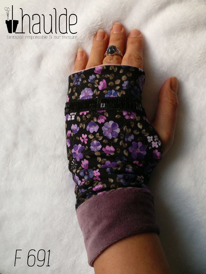 Paire de mitaines en jersey noir imprimé petites fleurs violettes. Un galon de deux rangs de sequins noirs décore au niveau des phalanges. Manchettes en velours mauve Vue de dessus, portée