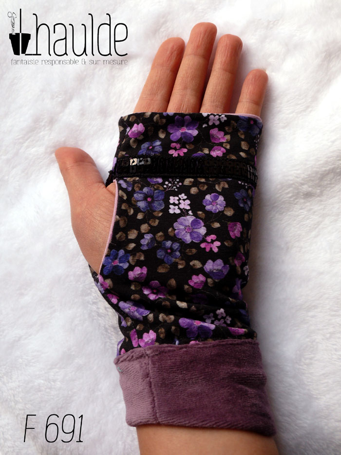 Paire de mitaines en jersey noir imprimé petites fleurs violettes. Un galon de deux rangs de sequins noirs décore au niveau des phalanges. Manchettes en velours mauve Vue côté paume, portée