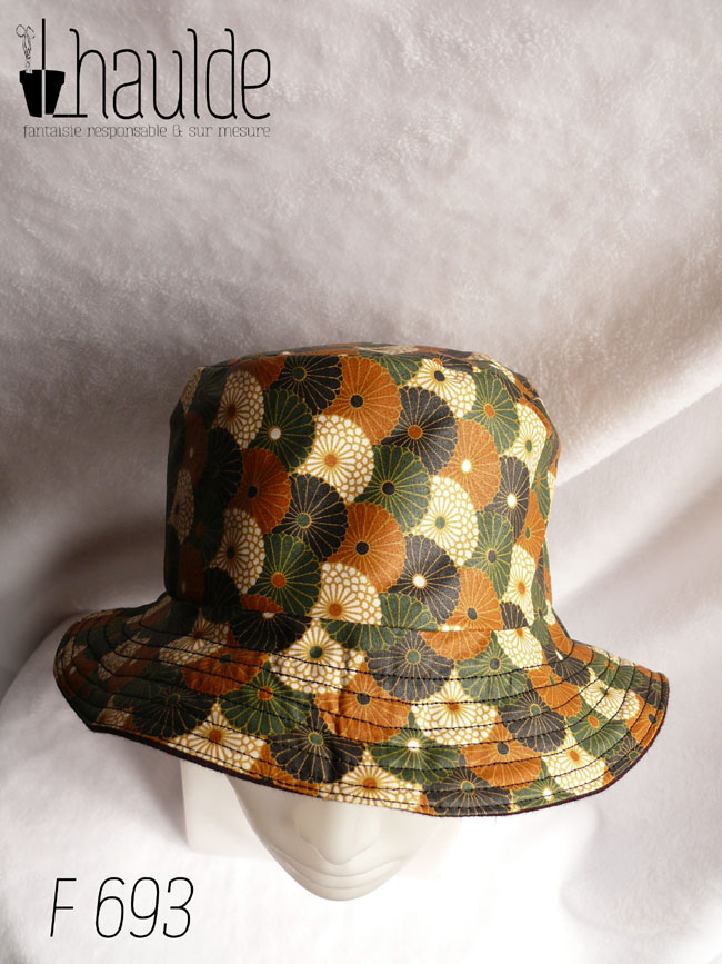 Bob en toile enduite imprimé de chrysanthèmes stylisés disposés en queue de paon, kaki, noir, ocre et blanc dans un style japonais L'autre face du bob est en laine Vu de dessus