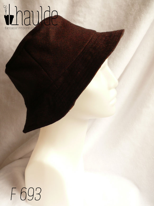 Bob en toile enduite imprimé de chrysanthèmes stylisés disposés en queue de paon, kaki, noir, ocre et blanc dans un style japonais L'autre face du bob est en laine Vu côté laine noir-rouge de profil sur une tête de mannequin