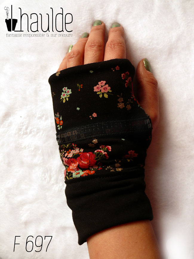 Paire de mitaines en jersey noir imprimé petits bouquets de roses rouges et autres fleurs. Au niveau du pouce un galon de deux rangs de sequins noirs traverse horizontalement la mitaine. Manchettes en jersey noir uni vue de dessus