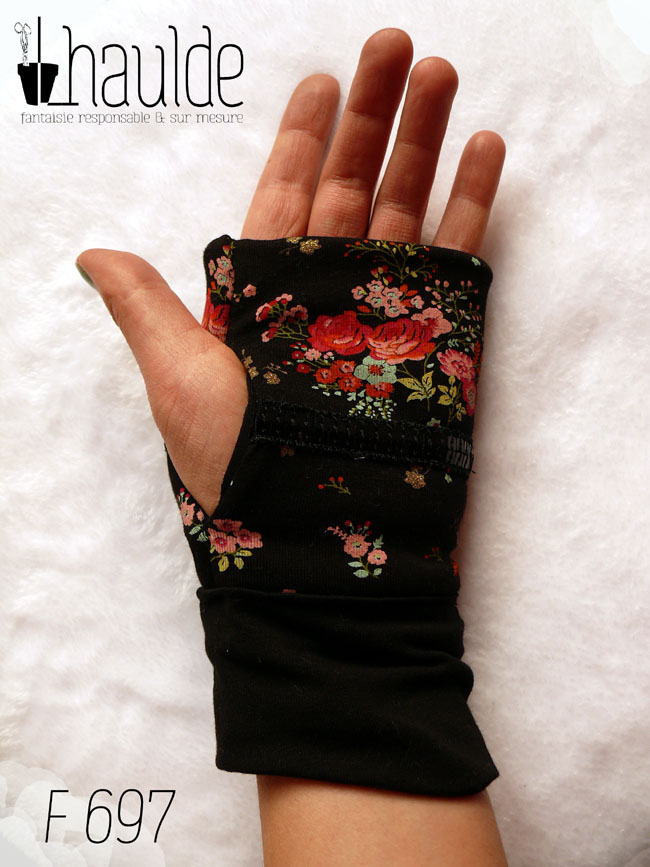 Paire de mitaines en jersey noir imprimé petits bouquets de roses rouges et autres fleurs. Au niveau du pouce un galon de deux rangs de sequins noirs traverse horizontalement la mitaine. Manchettes en jersey noir uni Vue côté paume