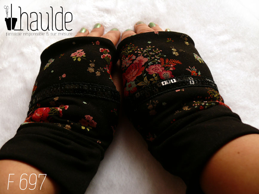 Paire de mitaines en jersey noir imprimé petits bouquets de roses rouges et autres fleurs. Au niveau du pouce un galon de deux rangs de sequins noirs traverse horizontalement la mitaine. Manchettes en jersey noir uni Vue de la paire portée