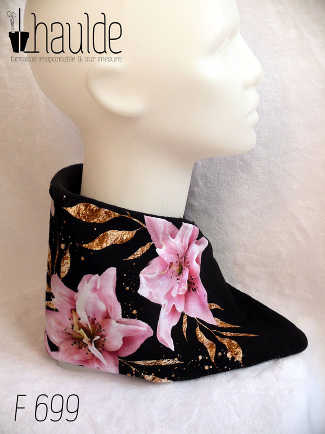 Tour de cou croisé en jersey noir imprimé fleurs de lys roses réalistes façon 3D avec un feuillage doré Doublure en polaire noire Vue de profil (droit) sur une tête de mannequin A noter que sur le profil gauche les lys sont minoritaires