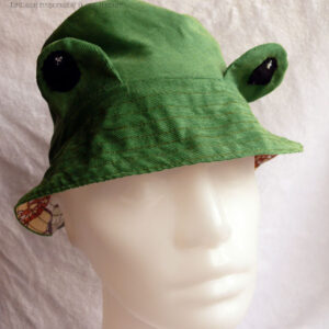 Bob réversible, vu du côté en milleraies vert avec des yeux qui dépassent La tête de mannequin est un peu trop grande pour ce chapeau pour enfant