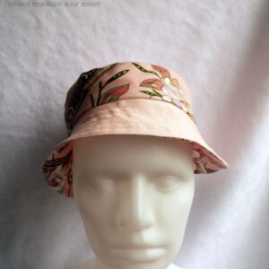 Bob court en toile rose et toile rose imprimée de motifs fleuris également roses et soulignés de vert foncé. Ici la bande centrale est en imprimé, le bord en uni rose Vu de face sur une tête de mannequin