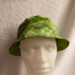 Bob court dans les tons verts, imprimé de motifs abstraits comme de l'aquarelle très humide. Vu de face sur une tête de mannequin