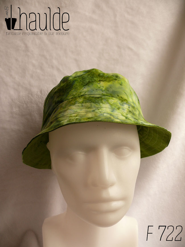 Bob court dans les tons verts, imprimé de motifs abstraits comme de l'aquarelle très humide. Vu de face sur une tête de mannequin