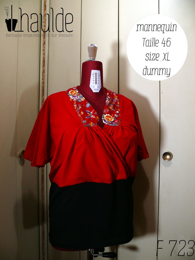 Haut coeur croisé à manches courtes en jersey rouge qui blouse jusqu'à la taille et jersey noir moulant de la taille aux hanches Le col est garni de tissu rouge imprimé fleurs et papillons d'inspiration Est asiatique, soulignés de doré. Vu de face sur un mannequin de couture réglé en taille 46